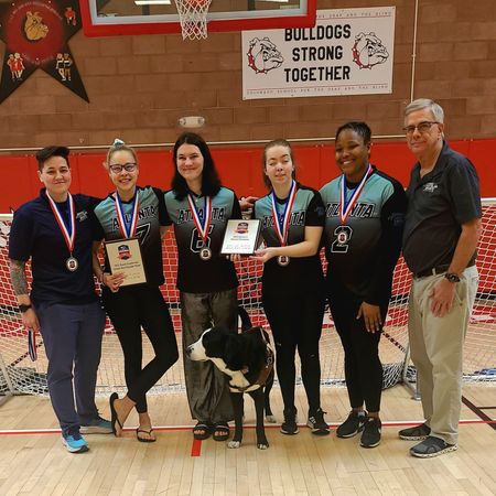 The Valkyries pose with their medals, MVP and National Champion plaques, and a service dog