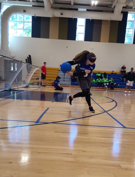 A Savannah player runs with the goalball during a match as teammates look on