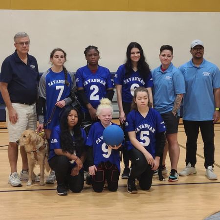 The Savannah girls goalball team poses together, including a player with a guide dog