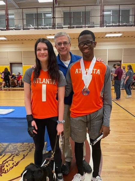 Atlanta goalball players and a coach stand together with a guide dog